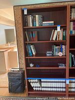 Full view of the dark brown wooden bookshelf filled with various books and small items. Shows the overall condition and structure of the bookshelf.