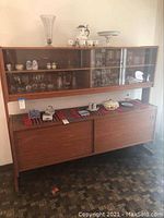 Front view of mid-century buffet with hutch, showing sliding doors on base and glass display cabinet on top