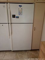 Front view of white Kenmore refrigerator showing top freezer and bottom fridge doors with magnets and stickers.