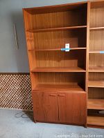 Full view of wooden bookshelf cabinet showing three open shelves and closed double doors below