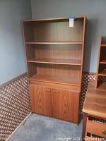 Front view of the wooden cabinet with three open shelves and closed two-door cabinet below.