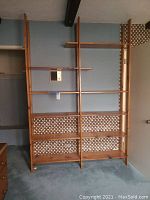 Front view of tall pine bookshelf with multiple shelves, attached vertically between two supports.