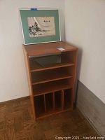 Light wood wooden cabinet with framing art on top