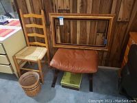 Wooden chair, leather cushioned bench, wicker basket and decorative picture frame arranged together