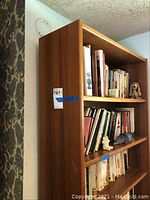 Full view of the wood bookcase filled with books and some small decorative items