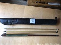 Full view of the pool cue shafts and the black carry case.