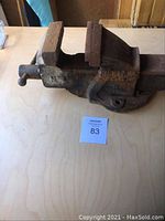 Front angle photo of a large, heavy metal bench vice with wooden jaw covers, showing the screw clamp handle and worn metal surfaces.