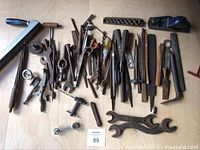 Photo showing the full assortment of hand tools including files, key wrenches, hand plane, and screwdrivers arranged on a wooden surface