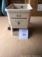 Front view of the beige plastic EZ Hand Spreader by Republic, showing the hopper with product name and logo.