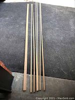 Several long narrow oak trim pieces laid out on the ground showing length and width.