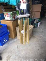 Wind chimes held by a hand showing six long gold tubes and stone top base