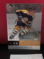 Front side of Bobby Orr NHL Legends hockey card in Boston Bruins uniform, showing player in action with stick.