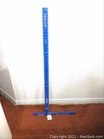 Photo of full blue metal square drywall tool standing against wall showing length and shape.