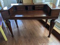 Front view of vintage secretary's desk showing writing surface, six small drawers, compartments, and four tapered legs.
