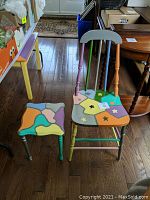Front view of the colorful hand-painted chair and matching mini side table showing artistic abstract patterns and star motifs.