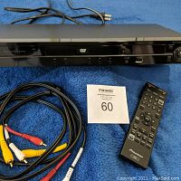 Pioneer DVD player with power cord, composite AV cables, and remote control on a blue surface.