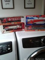 Four collectible tractor-trailer models in original boxes displayed on top of a washer/dryer unit, featuring Texaco and Flying J branding.