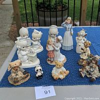 View of all 11 figurines on outdoor table, showing nurse themed and animal figures, including bears and panda