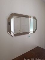 Mirror hung on wall reflecting white double-door closet and some surrounding room decor.