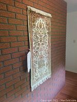 Full view of rug hanging on brick wall.