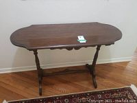 Front view of the antique wooden hall table showing the shaped top and turned legs.