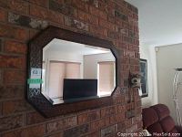 Front view showing antique wood framed wall mirror mounted on brick wall, dimensions label attached reading 32 x 21.