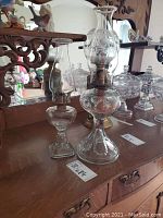 Two antique oil lamps, one larger with bullseye base and flared chimney, one smaller with square base