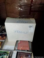 Closed cardboard box labeled Fragile, containing records and other items visible nearby.
