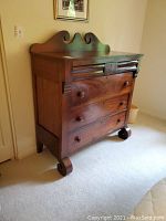 Front view showing entire six drawer dresser with carved crest and knob handles