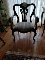 Front view of antique parlor chair showing dark wood frame with curved arms and legs, and patterned upholstered seat.