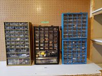 Three organizers of different sizes and colors (yellow, black, blue) with multiple drawers containing various small hardware items