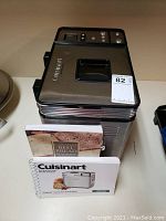 Top view of stainless steel Cuisinart bread maker with black control panel on top and two booklets in front.