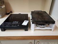 View of both the Salton induction hot plate and the metal base cooking griddle placed side by side on a counter.