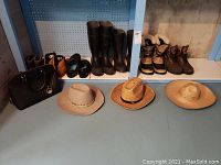 Overview photo showing three hats, black handbag, two pairs of tall boots and additional shoes on shelf behind.