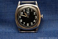 Front view of cushion-shaped metal case and black porcelain dial showing white Arabic numerals, star minute track, and Elgin USA winged shield logo