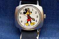 Close-up photo of the watch face showing Mickey Mouse with arms as hands and Swiss movement printed on the dial.