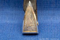 Close-up of the triangular watch face showing silver-tone case, worn dial with gold-tone hour markers and hands.