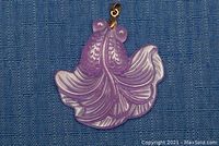 Front side showing detailed goldfish carving of scales and fins on purple jade pendant