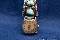 Front view of vintage B.W.C. Swiss windup watch with turquoise nugget silver band on blue background.