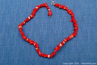 Full view of the red coral nugget bead necklace laid flat showing the entire length and broken clasp.