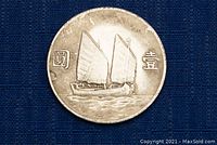Obverse side of the silver Chinese coin showing a traditional sailboat and Chinese characters.