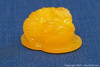 Front view of the yellow carved amber frog pendant showing detailed bumpy texture on the back and facial features.