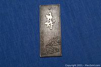 Rectangular old Japanese silver bronze mirror with engraved designs on a blue fabric background.