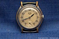 Front view of watch case and dial on blue fabric