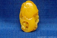 Front view of carved yellow amber pendant showing organic swirl design.