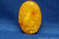 Close-up front view of the carved amber bird pendant showing detailed carving and coloration.