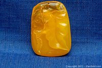 Front view of the amber pendant showing carved leaf motif with swirls and details.