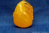 Amber carved lobster pendant shown upright on blue fabric background.