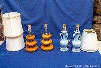 Two pairs of table lamps and four lampshades on blue backdrop, showing full items and condition.