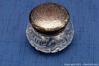 Top angled view of powder jar showing engraved sterling lid and clear pressed glass body.